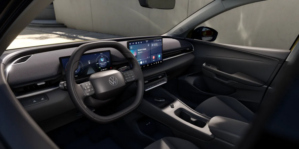 Interior of a Volkswagen showing a digital instrument cluster and large center touchscreen on the dashboard while parked in a bright space.