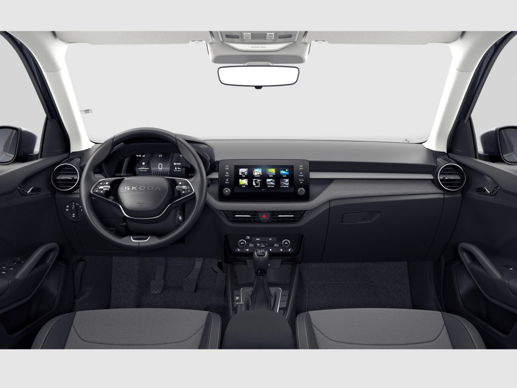 Interior view of a car cabin showing steering wheel, central touchscreen, and gear lever.