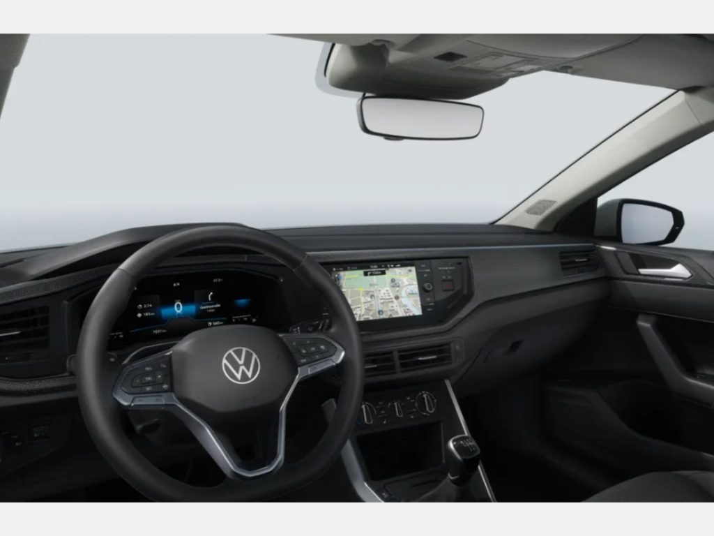 Driver's-seat view of a Volkswagen cockpit with steering wheel, digital dash, and center touchscreen nav display visible above the dashboard center console on the windshield.