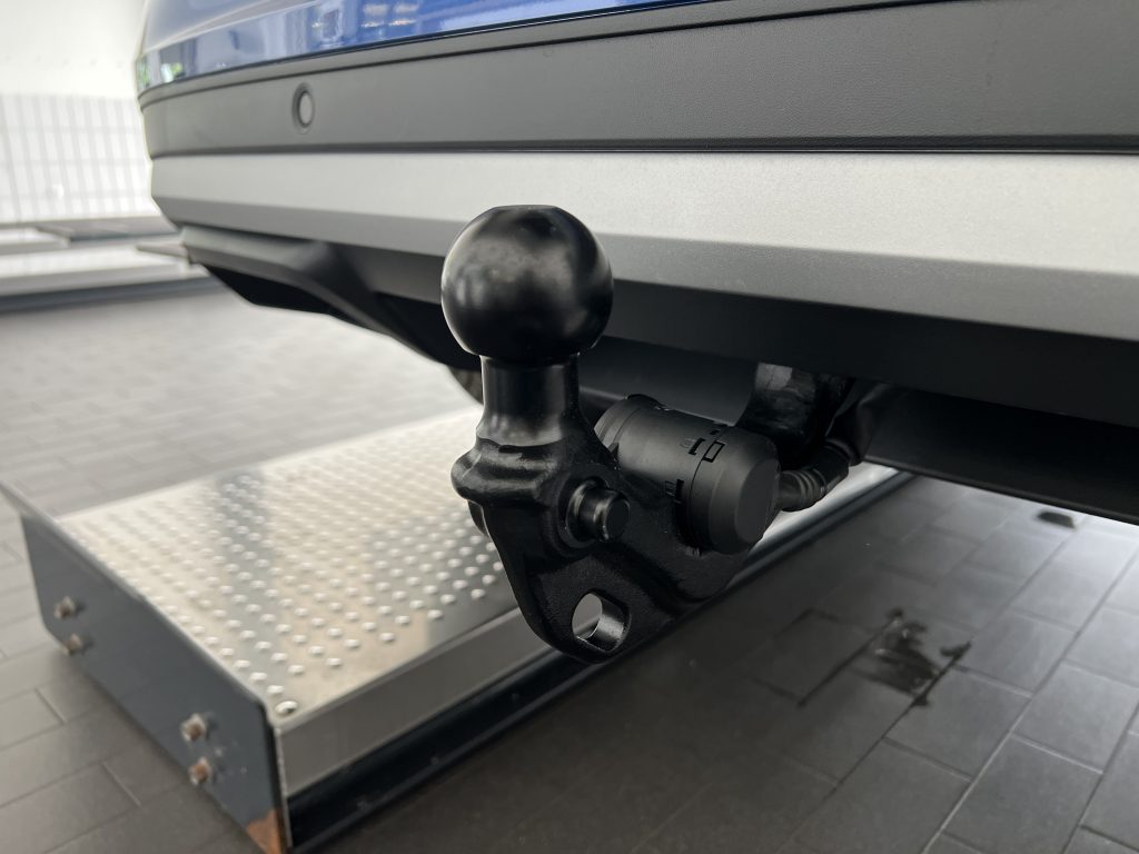Close-up of a trailer hitch ball attached to a tow bar under a vehicle.