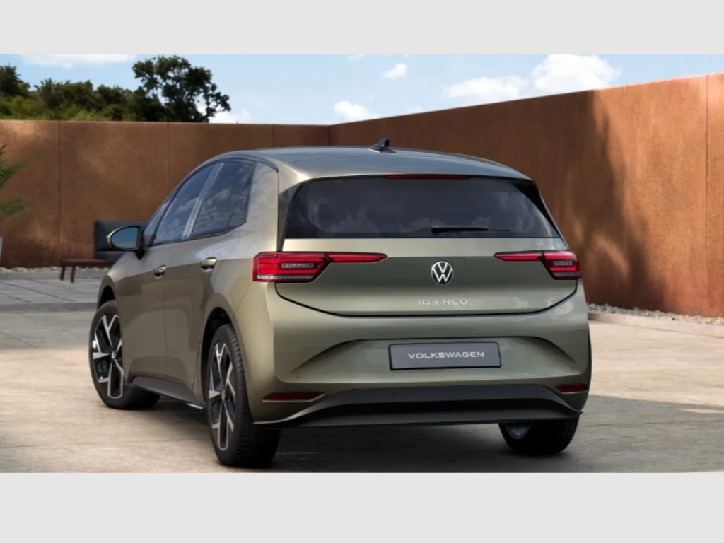 Rear view of a gray Volkswagen ID.3 Neo SUV parked in a driveway, with a tall brown brick wall and blue sky in the background.