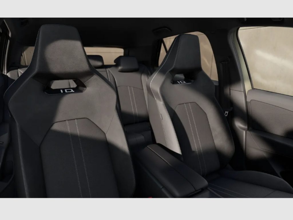 Inside a car cabin showing black fabric seats with white contrast stitching and headrests in a dark SUV interior.