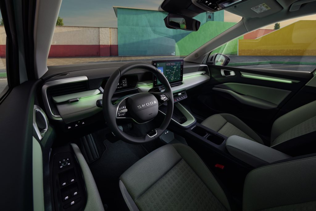 Interior of a modern car cabin centered on the steering wheel and large touchscreen navigation display with green ambient lighting.