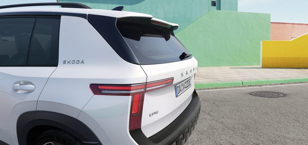 White Skoda SUV rear view parked on street with colorful pastel walls in the background.