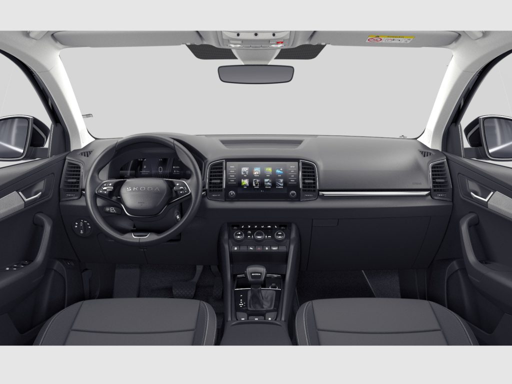 Interior view of a modern Skoda car: front seats, steering wheel, and central touchscreen dashboard seen from the rear seats beneath a gray background view of the windshield area.