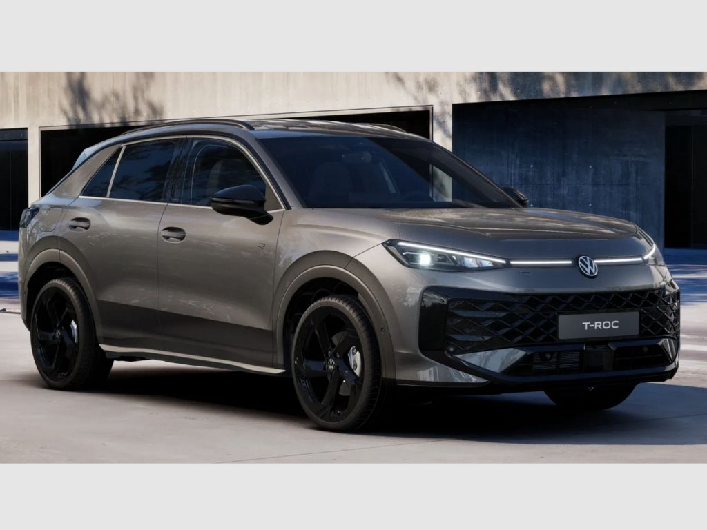 Gray Volkswagen T-Roc SUV parked in front of a modern concrete building, front angled view with black wheels and LED headlights.