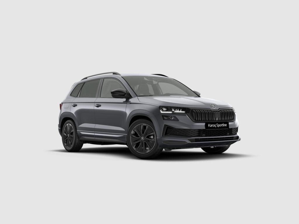 Front-left three-quarter view of a gray Skoda Karoq Sportline SUV against a light background with a prominent black grille and LED headlights.