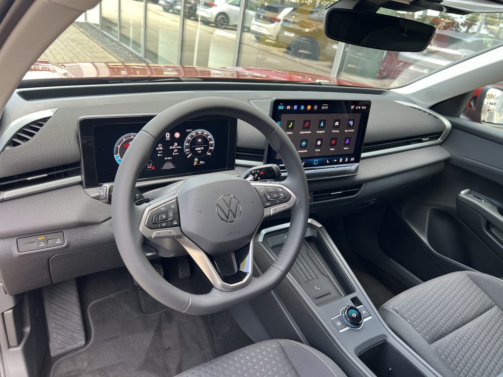 Interior of a modern car cockpit with a digital instrument cluster behind the steering wheel and a large touchscreen on the center console