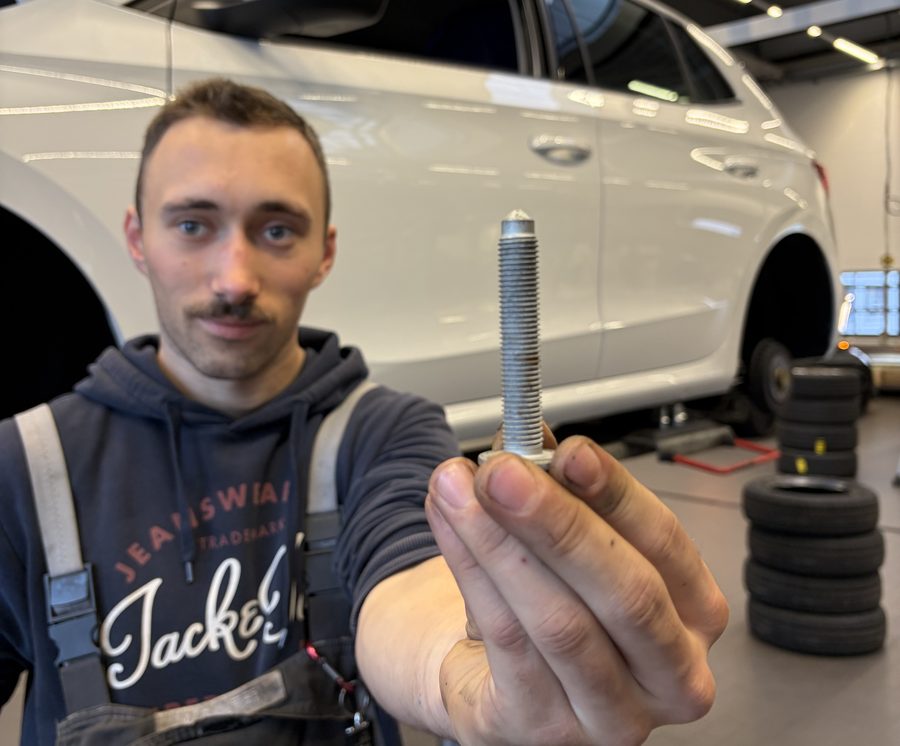 Mitarbeiter der Werkstatt von Autohaus Meyer Tostedt hält eine Schraube des Lenkgetriebes in die Kamera